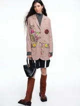 Blazer de corte recto con estampado de cuadros en tonos rosados, presenta bordados florales coloridos en el frente y un parche estilo escudo en el bolsillo superior. Cuenta con cierre frontal de botones y detalles en contraste en las mangas.
