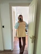 Buzo color beige con mangas celeste pastel y puños y ruedo acanalados.