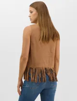 Blusa sin mangas de textura gamuzada color marrón, con escote redondo y corte recto. El frente presenta un diseño de calados circulares y geométricos, finalizando en un ruedo con flecos largos.