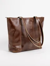 Cartera tote de cuero natural color beige, con doble asa larga para hombro y cierre superior con broche.