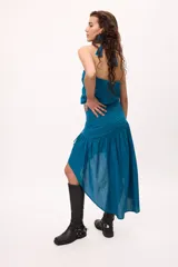 Falda azul con corte irregular, más corta en el frente y más larga en la parte trasera. Presenta volados en la parte inferior y frunces en la cintura.