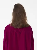 Camisa corta negra de terciopelo, de silueta cuadrada oversized, con bolsillo delantero y detalle en los puños y cuello con botón oro en forma de flor.