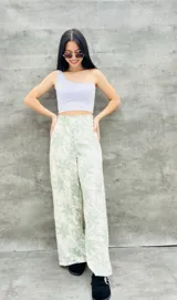 Pantalón palazzo estampado con flores color verde y blanco, de tiro alto y corte amplio.