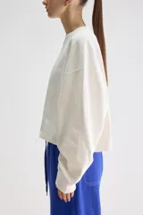 Remera oversize de manga larga y largo cropped color blanco, confeccionada en jersey de algodón, con cuello redondo y terminaciones desgastadas.