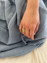 Anillo de diseño enlazado con textura irregular, realizado a mano en bronce. Presenta un diseño abierto que permite regular su tamaño con suavidad.