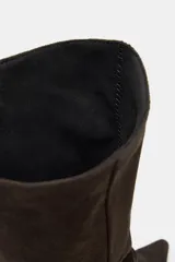 Bota de caña alta confeccionada en serraje, con diseño de punta fina y tacón fino. Presenta detalle de pespuntes en el cuerpo y sistema de calce pull-on.