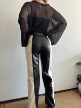 Pantalón largo de cuero sintético, corte recto, con diseño color block en blanco y negro.