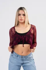 Blusa de encaje floral blanco con transparencias, mangas largas, escote cruzado y lazos frontales con volados.