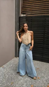 Top halter color beige, estilo chaleco corto, con cuello alto y bordes festoneados con costura decorativa.