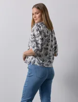 Blusa de gasa blanca con estampado de hojas en azul marino, cuello a la base con escote en V y botones, y mangas cortas abullonadas.