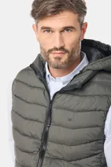 Chaleco capitoneado de color verde militar, con cierre frontal y capucha desmontable. Presenta un diseño acolchado con costuras horizontales y logo bordado en el pecho.