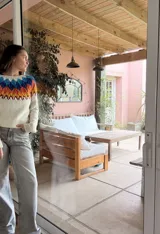 Sweater de punto tejido a mano, con diseño de guardas geométricas en colores azul, naranja y amarillo sobre base color crema. Presenta cuello redondo y mangas largas con puños acanalados.