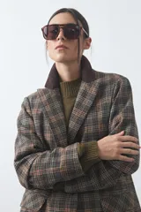 Blazer de corte relajado con estampado de cuadros tipo pied de poule en tonos rojizos y verdes. Presenta solapas clásicas en color azul oscuro y estructura definida.