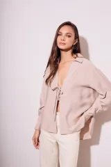 Blusa color visón con escote en V profundo y lazos ajustables en el frente, mangas largas y corte holgado.