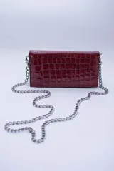 Cartera negra con textura símil cocodrilo y cadena metálica plateada.