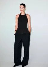 Top peplum negro con cuello halter, sin mangas y diseño entallado.