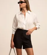 Short de sastrería negro, tiro alto, con cierre frontal de botones visibles.