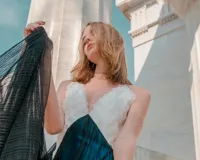 Vestido largo de fiesta con escote en V, parte superior blanca bordada con pétalos y falda plisada azul.