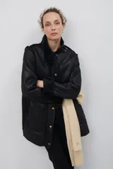 Chaquetón de efecto cuero en color marrón, con interior y detalles en corderito color bordó. Presenta cierre frontal con cremallera y botones a presión, cuello solapa y mangas largas con puños de corderito.