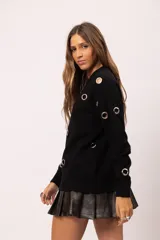 Buzo negro de cuello redondo con detalle de ojalillos metálicos plateados distribuidos en el frente y las mangas. Diseño de corte relajado con terminaciones acanaladas en cuello, puños y ruedo.