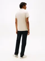 Chomba Tommy Hilfiger color beige, corte slim fit, con cuello clásico, tapeta de dos botones y logo bordado en el pecho.