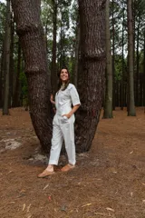 Mono blanco de gabardina de algodón, corte clásico con cierre frontal, pantalón largo con bolsillos, manga corta y cintura fruncida en la espalda.
