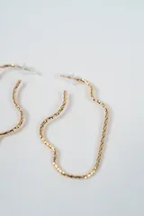 Par de caravanas de diseño abstracto con forma orgánica y textura retorcida, acabado en tono dorado.