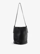 Cartera bandolera de cuero floater color negro, de diseño cilíndrico tipo bucket, con correa larga para llevar al hombro o cruzada y broche de imán.