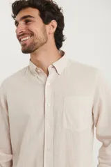 Camisa de manga larga confeccionada en una mezcla de algodón y lino, con cuello abotonado, cierre frontal de botones y un bolsillo en el pecho.