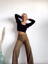 Pantalón acampanado color mostaza, de poliéster y rayón, con textura acanalada.