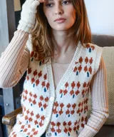 Chaleco tejido de punto color crudo, con diseño floral jacquard en tonos tierra, escote en V y cierre frontal con botones de nácar.