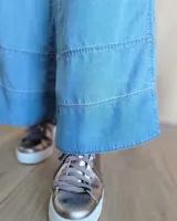 Pantalón de jean azul de corte palazzo con cintura alta y detalle de costuras horizontales en el ruedo.