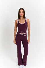 Conjunto deportivo compuesto por un top de escote redondo con ribetes blancos y una calza de tiro alto con cintura cruzada y detalle de ribete blanco. Ambas prendas son de color uva y cuentan con el logo bk. estampado en el top.