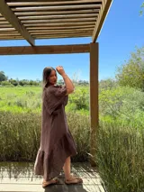 Vestido verde oliva de lino, corte suelto, con mangas abullonadas y volado en el ruedo.