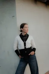 Saco tipo cardigan bicolor con diseño de bloques en blanco y negro, cuello en V, cierre frontal con botones y mangas largas con puños ajustados.