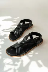 Sandalias chatitas de cuero en tono nude, con diseño de tiras cruzadas en el empeine y elástico en el talón para mayor ajuste. Presentan una plantilla acolchada y detalles en cuero charolado en la parte posterior.