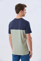 Remera de algodón y poliéster de corte clásico, con diseño en bloques de color negro en la parte superior y gris melange en la inferior. Presenta cuello redondo, mangas cortas y un pequeño estampado tipográfico en el pecho.