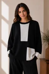Buzo de punto negro con diseño colorblock en gris, manga larga y puños con detalle brillante.