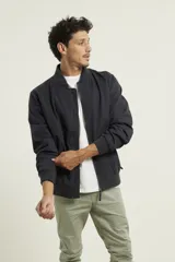 Campera tipo bomber color azul marino, 100% algodón, con cuello, puños y cintura tejidos al tono. Cierre frontal metálico.