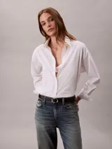 Camisa blanca de algodón con cuello camisero, manga larga y cierre frontal con botones. Presenta un sutil estampado integral de logo de Calvin Klein.