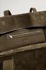 Bolso de viaje de diseño minimalista confeccionado en piel con acabado serraje. Cuenta con compartimento principal con cierre de cremallera e imanes, interior con bolsillos organizadores y doble asa de mano en piel.