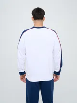 Buzo deportivo azul marino con detalles en rojo y blanco en cuello, hombros y mangas, de cuello redondo y manga larga, con el logo de Umbro y el escudo del Club Nacional de Football bordados en el pecho.