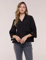Camisa negra de poliéster con cuello camisero, escote en V y cierre frontal de botones. Cuenta con mangas anchas de corte acampanado y detalles de bordado suizo calado en las mangas y en el ruedo inferior.