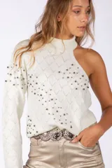 Sweater de punto negro con diseño asimétrico de un solo hombro y cuello alto. Presenta un patrón de rombos en relieve y está decorado con pequeñas tachas metálicas distribuidas por toda la prenda.