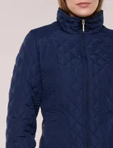 Campera capitoneada negra con costuras multidireccionales, cuello alto, cierre frontal y bolsillos laterales con cierre.