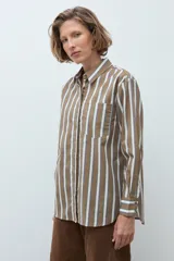 Camisa de corte clásico con estampado de rayas verticales en tonos khaki, blanco y azul. Presenta cuello camisero, cierre frontal con botones, bolsillo en el pecho y mangas largas con puños abotonados.