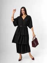 Vestido midi negro de crepé, con escote en V, mangas cortas amplias y diseño de capas escalonadas con volados. Incluye lazo al tono para ajustar la cintura.