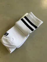 Medias blancas largas con dos rayas negras horizontales en la parte superior y logo vertical en el lateral.