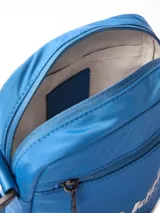 Cartera tipo reporter de Calvin Klein, color azul vibrante, con correa ajustable para llevar cruzada. Presenta un bolsillo exterior con cierre en la parte frontal y un bolsillo interior con ranura. El diseño destaca por el logo gráfico de Calvin Klein en blanco con texto adicional que indica "West 39th Street" y "New York City".