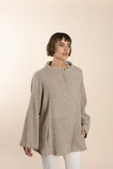 Capa de lana fina sin teñir, con estampado de espiga en tonos marrones y beige. Presenta cuello alto, mangas amplias, bolsillos laterales y pinzas en la parte delantera.